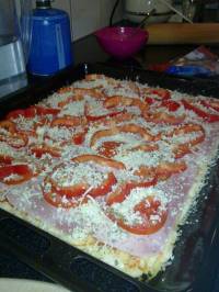 On complète la pizza avec les rondelles de tomate, les dés de poivrons et l'origan